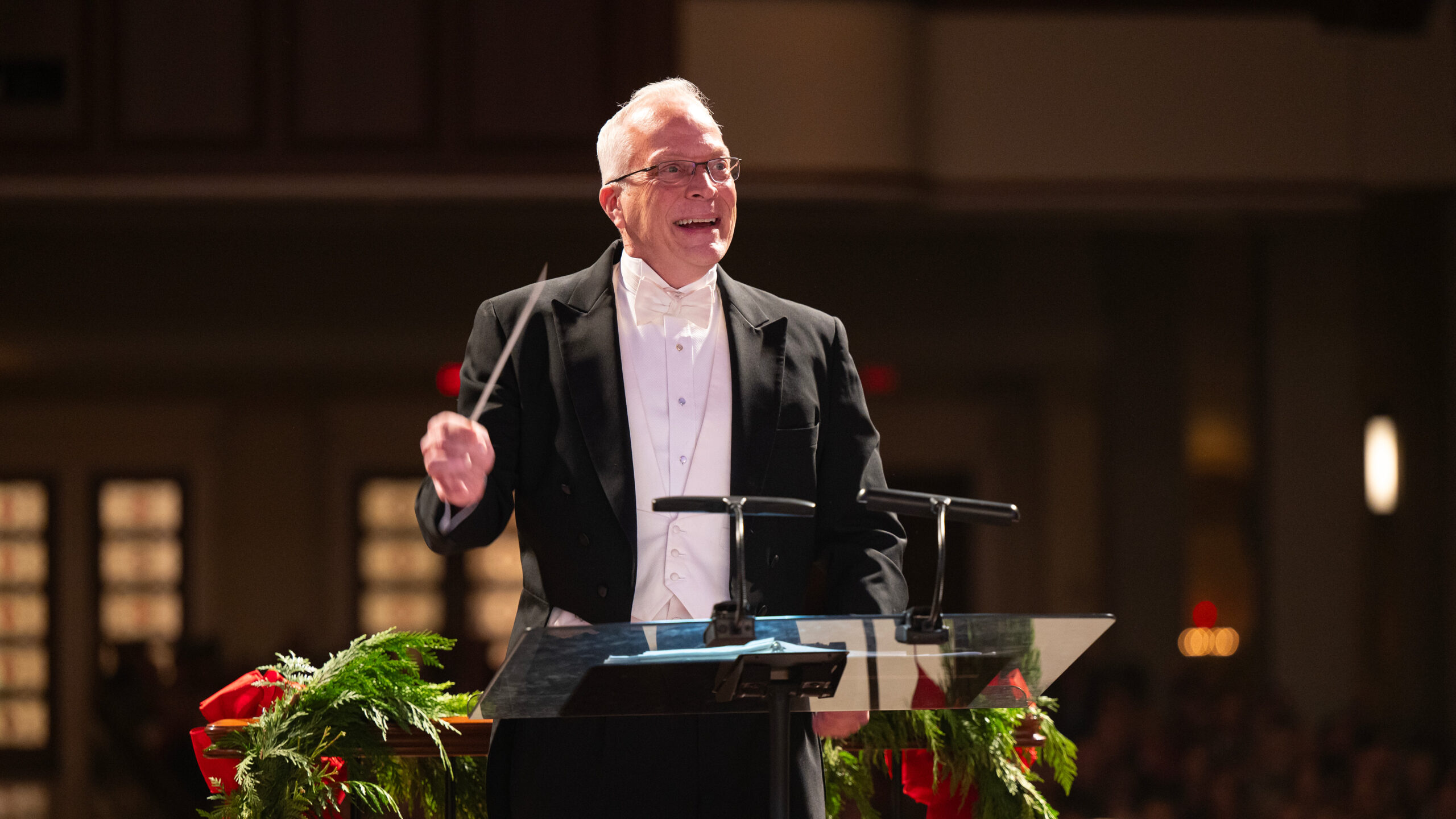 Scott Atchison conducting, smiling in a tux.